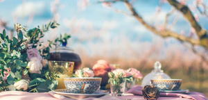 outdoor whimsical tea party with cherry tree and blue sky in background and table with teacups in forefront