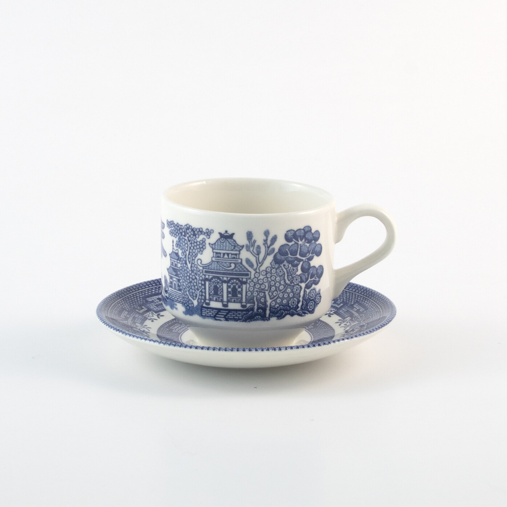 blue and white tea cup and saucer with country designs