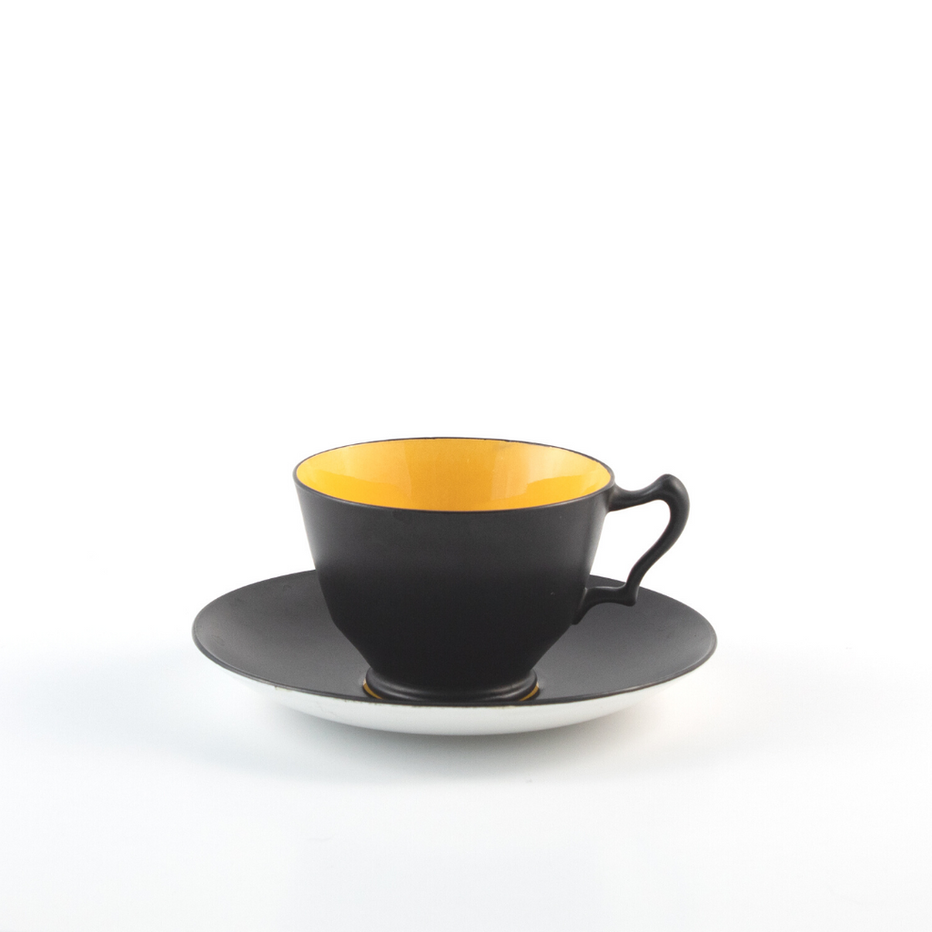 black matte teacup with bright yellow inside on black saucer